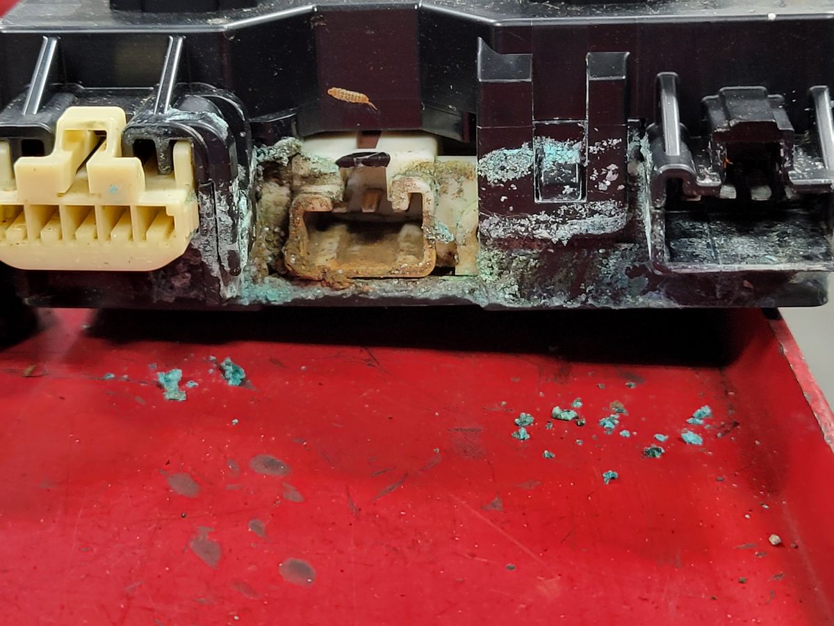 Toyota Highlander Hybrid system main relay (SMR) block removed, showing heavy green corrosion on the terminals caused by water intrusion